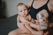 © Алина Троева - Young mother with newborn cute infant naked baby boy, holding him on arms, using breast pump hugging and breastfeeds with breast milk. Healthy child, concept of hospital and happy motherhood. Nursery.