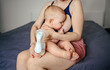 © Алина Троева - Young mother with newborn cute infant naked baby boy, holding him on arms, using breast pump hugging and breastfeeds with breast milk. Healthy child, concept of hospital and happy motherhood. Nursery.