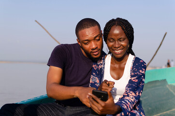 young cute african couple feeling happy as they use their cellphone