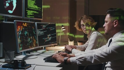Mature Caucasian man and young woman staying late at work in office working on hacker attack prevention