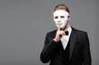 © LIGHTFIELD STUDIOS - young businessman in face mask showing secret gesture isolated on grey