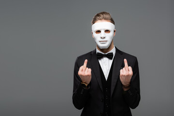 Wall Mural - businessman showing middle fingers while wearing face mask isolated on grey