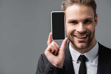 Wall Mural - successful businessman showing mobile phone with blank screen isolated on grey