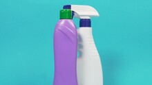 A White Bottle Of Window Cleaning Spray, A Purple One With Household Chemicals, A Sponge And A Duster. Blue Solid Color Background. Tools For Cleaning The House.