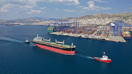 Aerial drone photo of cargo carrier tanker leaving industrial port of Perama with the help of tug boats for Mediterranean destination, Attica, Greece