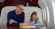 Father and daughter drawing with colorful pencils flying together on private jet