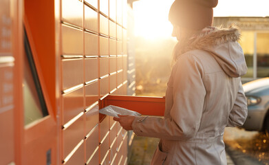 Wall Mural - Woman picks up mail from automated self-service post terminal machine.