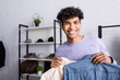 © LIGHTFIELD STUDIOS - Arfican american businessman holding shirts on hangers and smiling at camera in showroom
