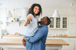 © Vadim Pastuh - Happy cheerful multiracial newlyweds moved in new house, handsome black guy carrying beautiful biracial woman on his arms, smiled female shows keys at the camera. Mortgage and real estate concept