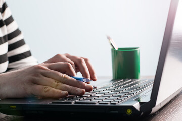 Hands and laptop keyboard close-up, soft focus. A man or woman uses a laptop to study online, work, search for information on the Internet.