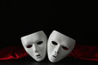 White theatre masks and red fabric on black background