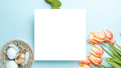 Wall Mural - Golden easter colour eggs in basket with spring tulips, white feathers on pastel blue background in Happy Easter decoration. Spring holiday top view concept.