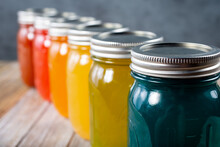 A View Of A Row Of Glass Mason Jars With A Rainbow Color Scheme.