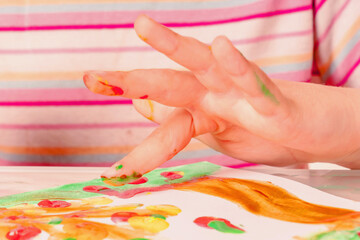 Close up beautiful young girl painting picture with colorful painted fingers. Horizontal image.