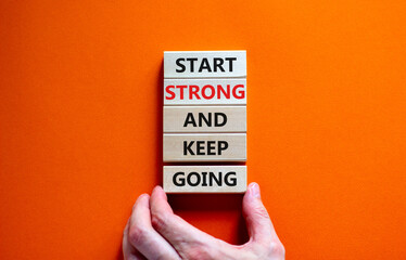 Start strong and keep going symbol. Concept words 'Start strong and keep going' on wooden blocks on a beautiful orange background. Businessman hand. Business, motivational and start strong concept.