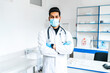Portrait of a handsome Asian male doctor in medical clothes and with a stethoscope. he is in a protective mask, modern medicine, hospital, internship. modern hospital