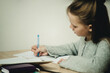 © Marina - teen girl writing at the table on a white background