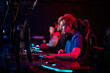 Training bootcamp for professional esports players. Young cyber-athletes play an online shooter game. Glowing keyboard, neon light.