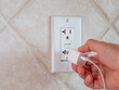 © Scott Habermann - Plugging in electrical usb cord and charger plug in wall outlet. Cell phone power adapter brick and cord in GFCI wall plug.
