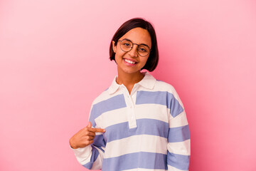 Young mixed race woman isolated on pink background person pointing by hand to a shirt copy space, proud and confident