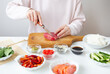 © Artsaba Family - The process of preparing sushi, preparing all the ingredients for sushi, the girl cuts the tuna.
