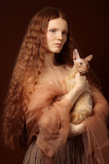 Portrait of beautiful red head girl in brown dress with cat in hands