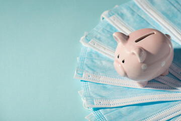 Overhead photo of piggybank pink pig with pile of masks isolated on the blue background