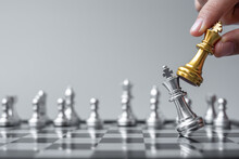 Businessman Hand Moving Gold Chess King Figure And Checkmate Opponent During Chessboard Competition. Strategy, Success, Management, Business Planning, Disruption And Leadership Concept