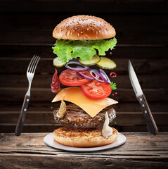 Wall Mural - Fast food concept - flying hamburgers ingredients on a wooden background.