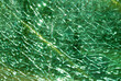 Close-up of a green colored broken fragmented glass window shield, with a yellow line