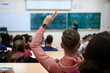 The student raises his hands asking a question in class in college