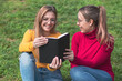© EVA CARRE - Two women enjoying reading a book in a park