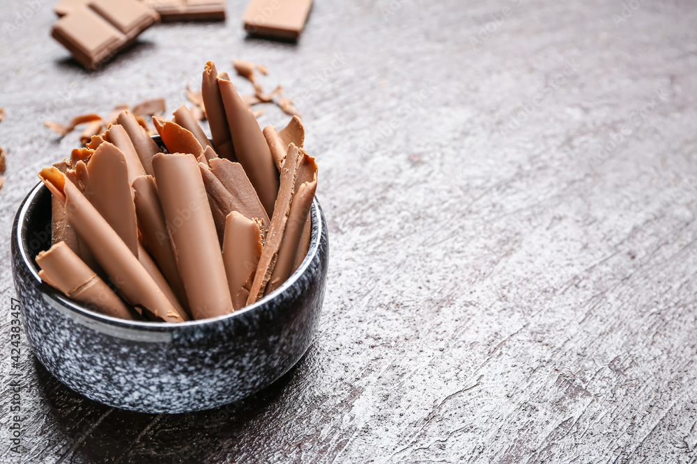 Bowl with tasty chocolate curls on dark background