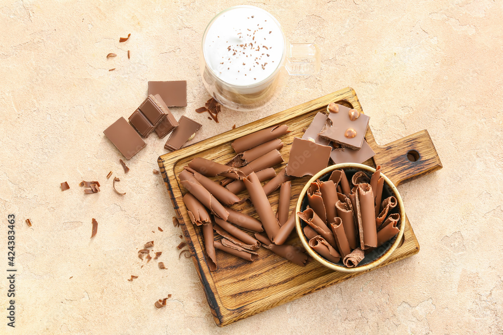 Board with delicious chocolate curls on light background