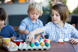 © Tomsickova - Sweet children, brothers, coloring and paiting eggs for Easter in garden, outdoor at home in backyard