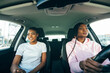 © F8  \ Suport Ukraine - Two attractive young african girlfriends talking and laughing together while driving in a car through the city on a sunny day.