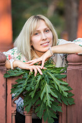 Wall Mural - Portrait of a young blonde girl with a green papaya leaf