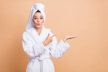 Photo of shocked young pretty woman wear turban point hold hand empty space recommend isolated on beige color background