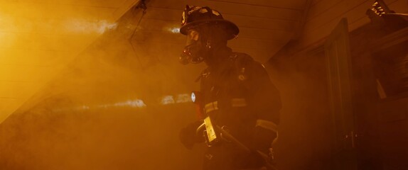 Dramatic silhouette of American firefighter in full gear exploring the huge fire zone