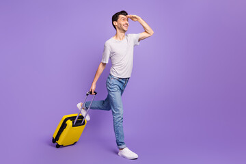 Poster - Photo of excited guy walk hold case palm forehead look empty space wear t-shirt jeans sneakers isolated purple background