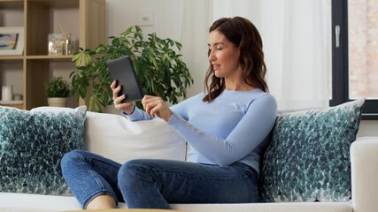 Sticker - people, technology and leisure concept - happy young woman sitting on sofa with tablet pc computer having video call and waving hand at home