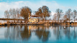 Fototapeta Tęcza - Beautiful winter landscape on a sunny day with a church and reflections in a frozen pond near Wallersdorf, Bavaria, Germany
