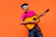 © deagreez - Photo portrait of curious dreamy man laughing playing guitar looking blank space isolated vibrant orange color background