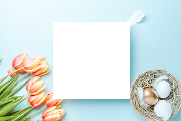 Wall Mural - Easter eggs background. Golden, white colour egg in basket with spring tulips, feathers on pastel blue background in Happy Easter decoration. Foil minimalist egg design, modern top view template.