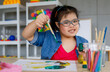 © Bangkok Click Studio - Young Asian down syndrome little girl sitting at desk with colors and painting with concentrated and calm. painting. Concept for education for disabled kid