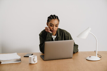 Black young woman working with laptop while sitting at table