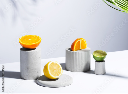 Obraz Dibond Citrus still life concept with lemon,lime and orange on gray stands and podiums over white background, horizontal