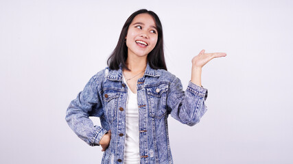 Asian woman smiling wearing jeans jacket and  pointing finger hands up with isolated white background