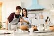 © sirikorn - A couple uses their smart phone to take a picture while admiring his wife's cooking work With a happy face in an atmosphere of love