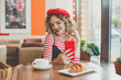 © artmim - Cute happy young woman with smartphone in cafe